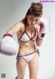 A woman in a bikini and boxing gloves posing for a picture.